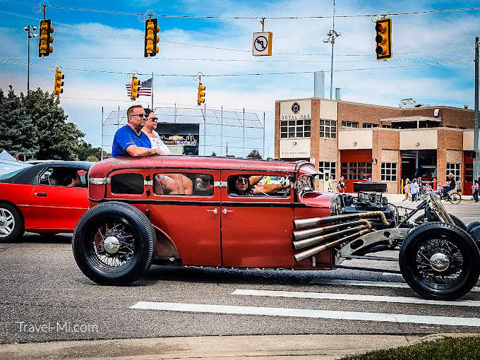 Two people riding in the back of a modified red car